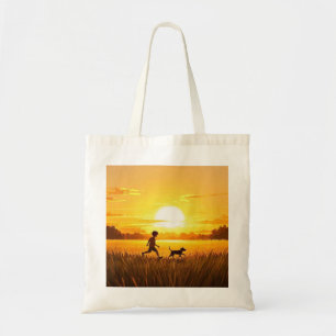 Junge Junge, die mit Hund bei Sonnenuntergang renn Tragetasche