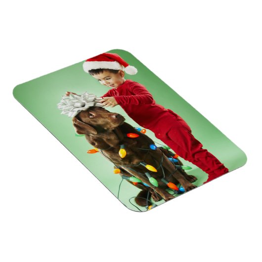 Junge Junge packt Weihnachtsleuchten um einen Hund Magnet (Rechte Seite)