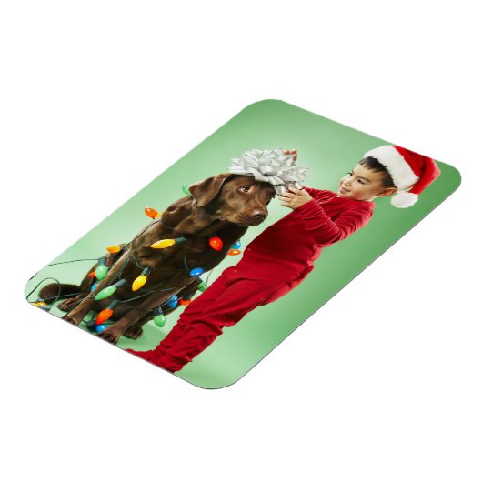 Junge Junge packt Weihnachtsleuchten um einen Hund Magnet (Linke Seite)
