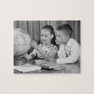 Junge und Mädchen betrachten Globus Puzzle