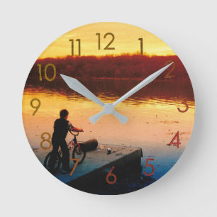 Jungen auf einem Fahrrad bei Sonnenuntergang Wandu Runde Wanduhr