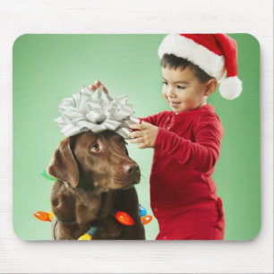 Junger Junge, der Weihnachtslichter um einen Hund Mousepad