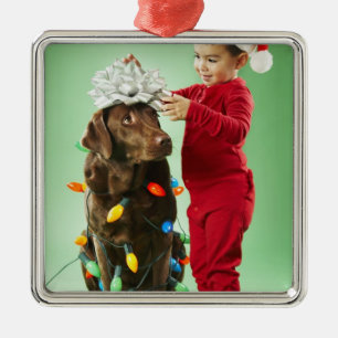 Junger Junge, der Weihnachtslichter um einen Hund Silbernes Ornament