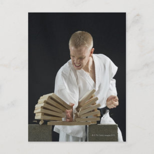 Junger Mann bricht Bretter mit Karate-Chop auf Postkarte