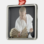 Junger Mann, der an Bretter mit Karatehieb bricht Silbernes Ornament (Links)