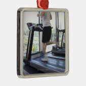 Junger Mann, der auf eine Tretmühle am Ornament Aus Metall (Rechts)