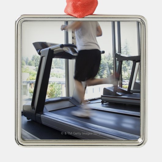 Junger Mann, der auf eine Tretmühle am Ornament Aus Metall (Vorne)