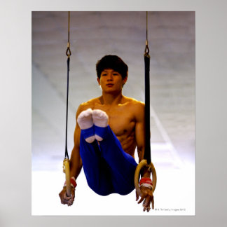 Junger Mann, der Gymnastikringe praktiziert Poster