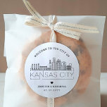 Kansas City Skyline | Begrüßungsnachricht Runder Aufkleber<br><div class="desc">Erweitern Sie Ihre Hochzeitspakete oder Event-Gastgeschenke mit einem individuellen Set von Begrüßungsaufklebern! Diese eleganten, aber minimalen Aufkleber sind auf eine Hochzeit in der schönen Stadt Kansas City zugeschnitten. Sie verfügen über eine moderne Skyline aus Deko, die den Namen der Stadt trägt und darunter integriert ist. Alle Elemente des Designs, einschließlich...</div>