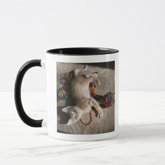 Kätzchen, das mit Garn spielt Tasse (Links)