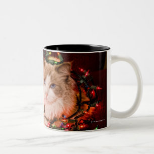 Katze, die auf einem Ball der Weihnachtslichter Zweifarbige Tasse