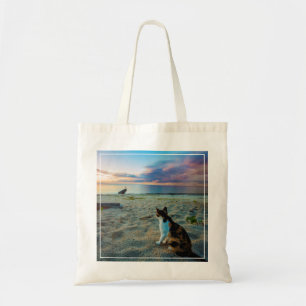 Katze, die auf einem Strand sitzt Tragetasche