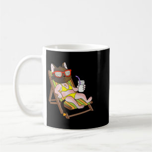 Katze im Bikini auf einem Strandstuhl trinkend Kaffeetasse