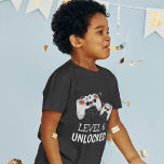 Kids Video Gaming T-Shirt<br><div class="desc">Diese coolen Gamer-Tshirts mit zwei Gaming-Kontrolle-Pads auf einem schwarzen Hintergrund,  mit spielerischem Text,  der "LEVEL 6 UNLOCKED" und "IHR NAME UND ALTER" lautet. Alle Stile und Farben des Schriftartes können geändert werden,  indem Sie nach der Personalisierung auf den entsprechenden Link klicken.</div>