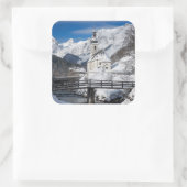 Kirche im Schnee mit den Alpen Quadratischer Aufkleber (Tasche)