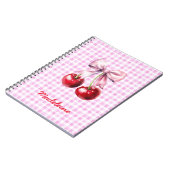 Kirsche mit süßem rosa Schleifchen auf Gingham mit Notizblock (Linke Seite)