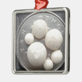 Kleine versteinerte Seeigel auf einem Stück 10p Silbernes Ornament (Links)