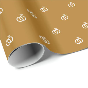 Kleine weiße Eheringe auf mattgoldenem Hintergrund Geschenkpapier