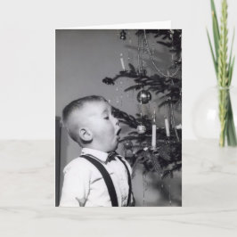 Kleiner Junge bläst Kerze auf Weihnachtsbaum aus Feiertagskarte