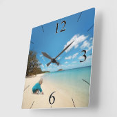 Kleines Mädchen am Strand mit Seashells Quadratische Wanduhr (Winkel)