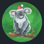 Koala Bear Christmas Runder Aufkleber<br><div class="desc">Feierliche Weihnachtslieferungen aus dem Koala-Bären zeigen unseren kuscheligen Koala-Bär mit einer Weihnachtsmannmütze. Viele unserer lustigen Urlaubsprodukte zeigen auch unser niedliches Koala von hinten mit — überraschend! — Baby Koala mit einem heiligen Kranz. Viele Designs haben auch ein Weihnachtsgrün mit unserer Signatur-Textur. Genießen Sie die Shoppingsaison mit unseren niedlichen und kuscheligen...</div>