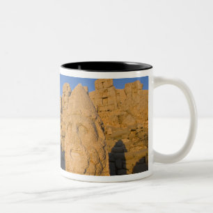 Kolossale Kopfstatuen von Göttern bewachen die 2 Zweifarbige Tasse