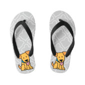 Labrador-Retrieverwelpenhund sitzen goldenen Kinderbadesandalen (Fußbett)