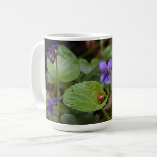 Ladybug über süße Violettsorten-Blume Kaffeetasse