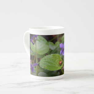 Ladybug über süße Violettsorten-Blume Porzellantasse
