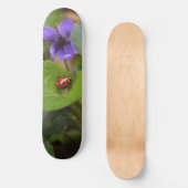 Ladybug über süße Violettsorten-Blume Skateboard (Vorderseite)