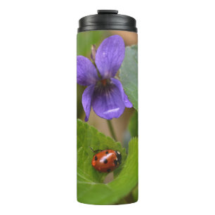 Ladybug über süße Violettsorten-Blume Thermosbecher