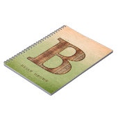 Letter-B-Holzkorn auf grünem beigem Grunge Notizblock (Linke Seite)