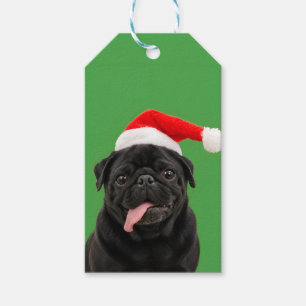 Lustiger schwarzer Mops mit Weihnachtsmannmütze un Geschenkanhänger