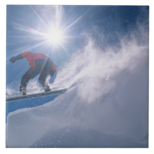 Man springt von einer großen Ecke auf einem Snowbo Fliese