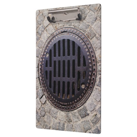 Manhole-Abdeckung und Kopfsteinpflasterstraße Klemmbrett (Links)