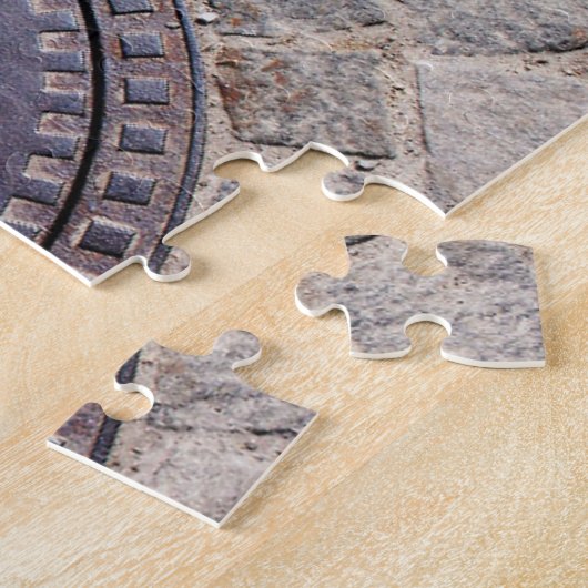 Manhole-Abdeckung und Kopfsteinpflasterstraße Puzzle (Seite)