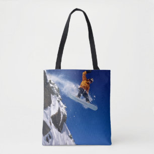 Mann auf einem Snowboard springt von einer Schneek Tasche