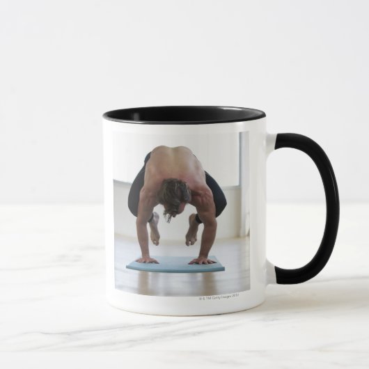 Mann, der Training auf Yogamatte tut Tasse (Rechts)