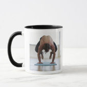 Mann, der Training auf Yogamatte tut Tasse (Links)