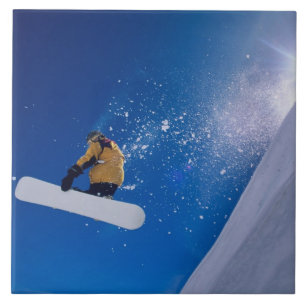 Mann fliegt auf einem Snowboard durch die Luft mit Fliese