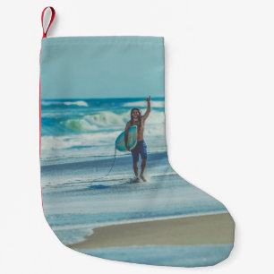 Mann mit Surfbrett am Strand Kleiner Weihnachtsstrumpf