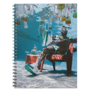 Mann sitzt auf Stuhl unter Wasser mit schwimmendem Notizblock