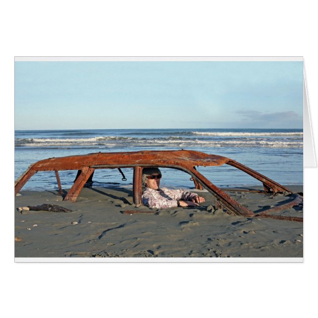 Mann sitzt in einem rostigen Auto am Strand (Vorderseite (Horizontal))