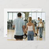 Mann und Frau heben Handgewichte vor einem Postkarte (Vorne/Hinten)