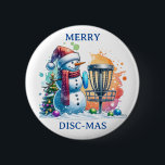 Merry Disk-mas | Disk Golf Christmas Button<br><div class="desc">Niedlicher Cartoon Snowman in Weihnachtsmannmütze neben einem Discgolf im Schnee neben einem Weihnachtsbaum.</div>