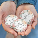 Midsommer Floral Bridesmaid Button<br><div class="desc">Identifizieren Sie die Hauptakteure in Ihrem Brautparty mit unseren eleganten,  süß-schicken Blumenknöpfen. Button ist mit einem Blumenkranz in Aquarellfarben mit peachy rosa Bacheleien,  weißen Hydrangea-Blume und botanischem Grün ausgestattet,  der in handgeschriebenen Schriftzeichen mit "Bräute" beschriftet ist.</div>