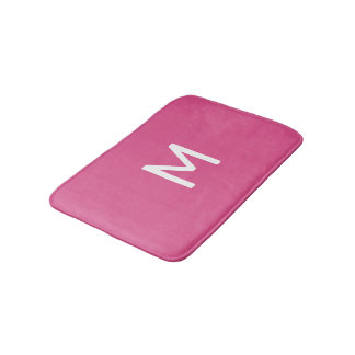 Minimalistisches weißes Monogramm auf rosa Badematte