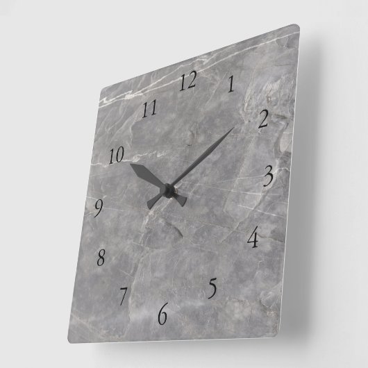 Moderne Uhr an der Wand aus grauem weißem Stein (Winkel)