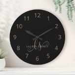 Modernes Schwarzes Gold Feminin Script Mit Monogra<br><div class="desc">Modernes Schwarzes Gold Feminine Script Mit Monogramm große Uhr. Diese elegante,  große Uhr lässt sich einfach mit Ihrem eigenen Monogramm und Namen personalisieren.</div>