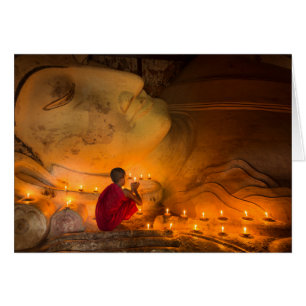 Mönch beim Gebet neben einem Buddha